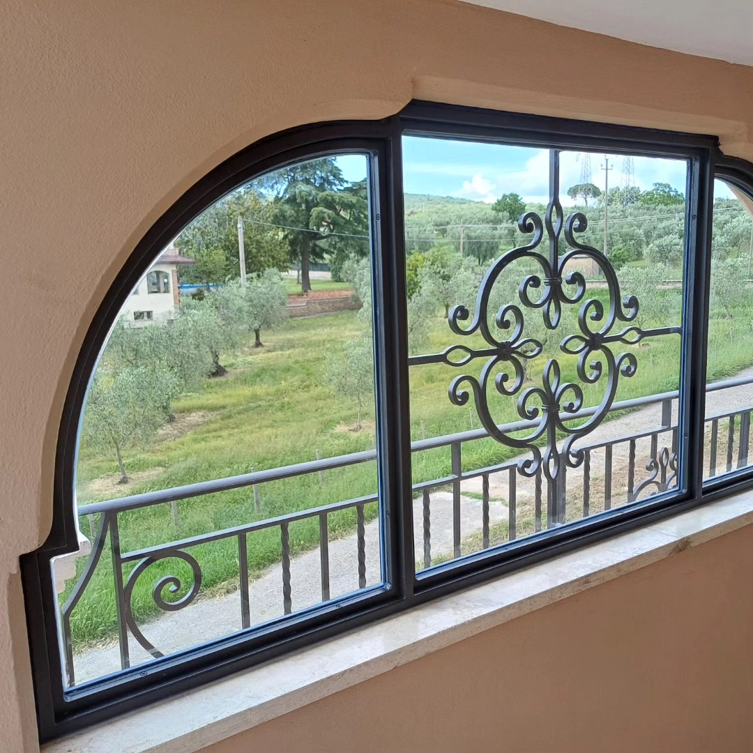 Finestra ad arco in ferro con decoro battuto
